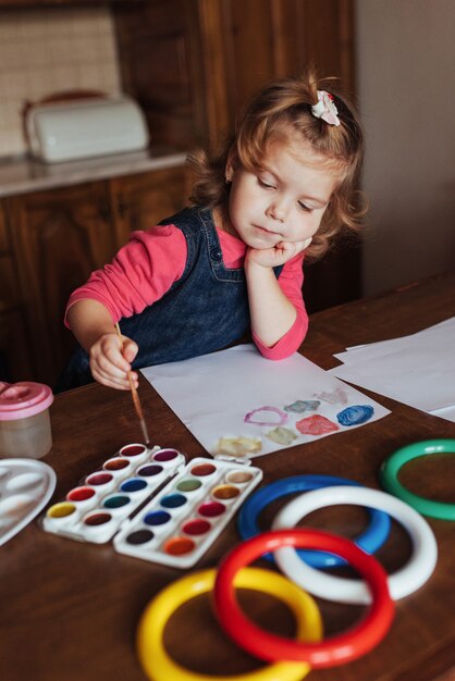 Cute little girl draws a circle of colored paints