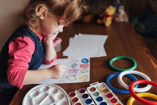 かわいい女の子が色の塗料の輪を描く