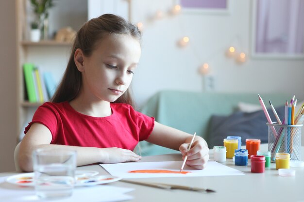 Милая маленькая девочка рисует краски дома