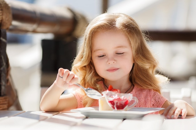 cute little girl eating dessert in cafe terrace