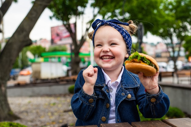 Cute little girl eating a hamburger in the restaurant