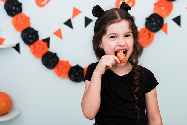 Cute little girl eating a pumpking candy