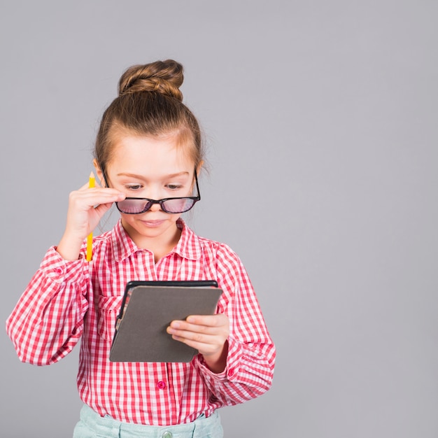 Cute little girl in glasses using tablet