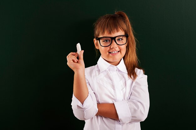 Cute little girl in glasses with chalk in hand