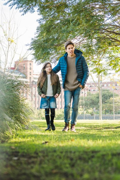 かわいい少女と父親が一緒に芝生を歩く