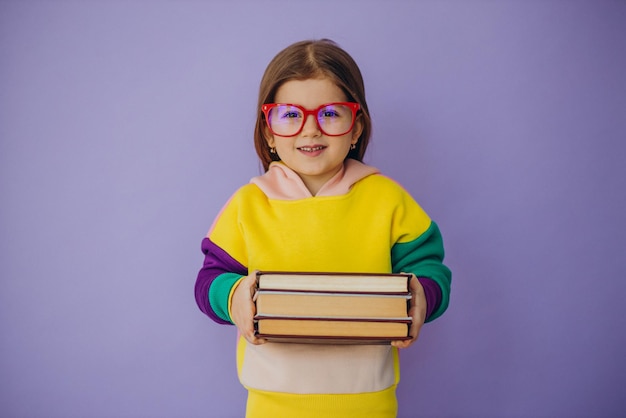 Cute little girl holding books isolated in studio