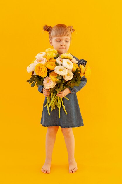Милая маленькая девочка с цветами в руках