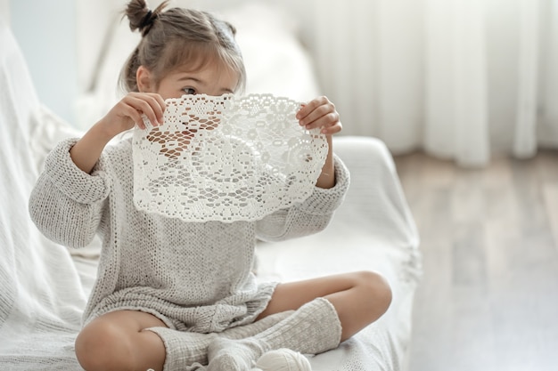 Cute little girl holding a handmade openwork napkin in her hands.