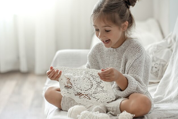 cute little girl holding a handmade openwork napkin in her hands.