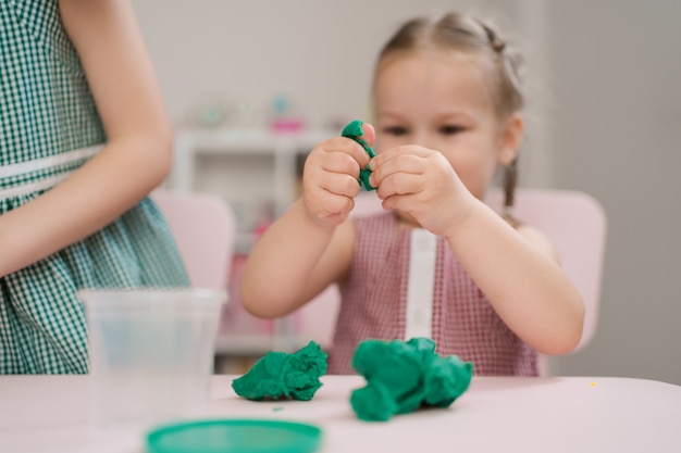 Cute little girl moulds from plasticine on table