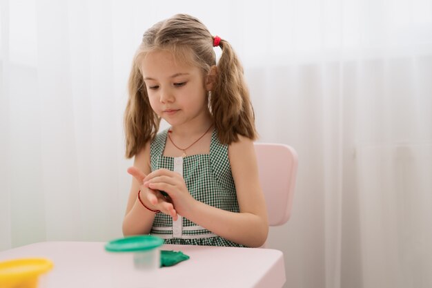 Cute little girl moulds from plasticine on table