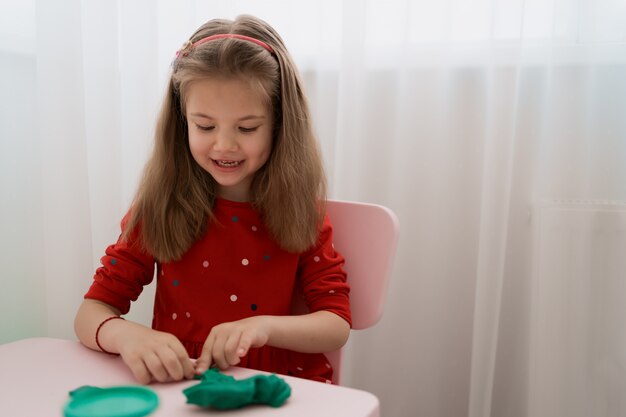 Cute little girl moulds from plasticine on table