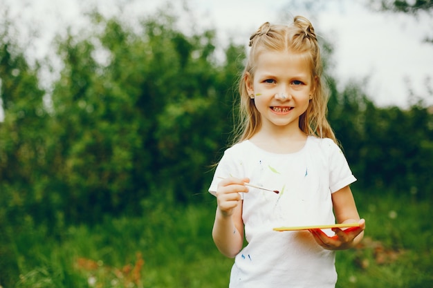 Cute little girl painting in a park