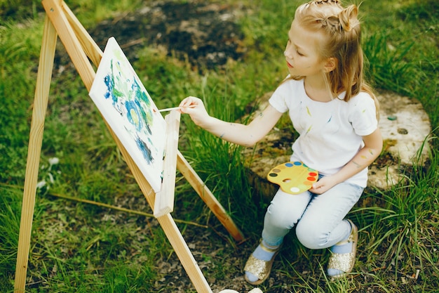 Free photo cute little girl painting in a park