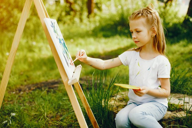 Cute little girl painting in a park