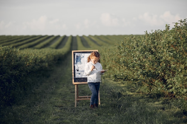 Cute little girl painting in a park