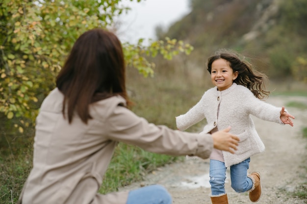 Cute little girl. People walks outside. Woman in a brown coat.