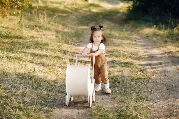 Cute little girl playing in a park with white carriage