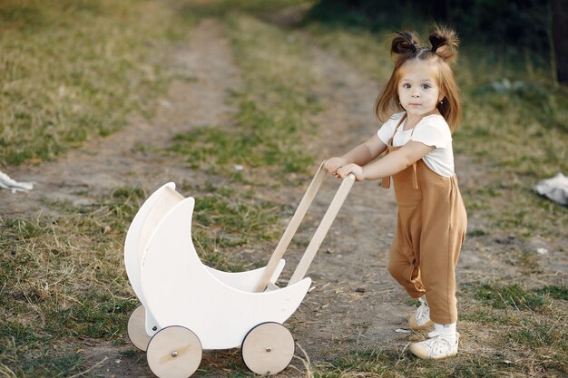 Cute little girl playing in a park with white carriage