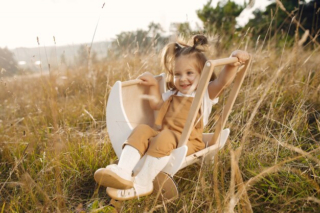 Free photo cute little girl playing in a park with white carriage