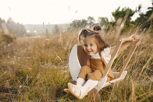 Милая маленькая девочка, играя в парке с белой коляской