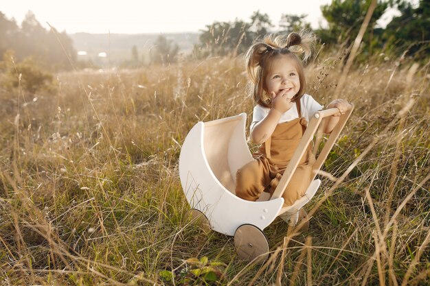 Cute little girl playing in a park with white carriage