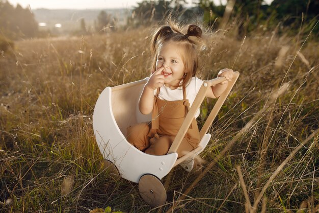 Cute little girl playing in a park with white carriage