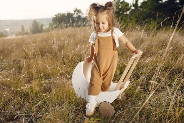 Cute little girl playing in a park with white carriage