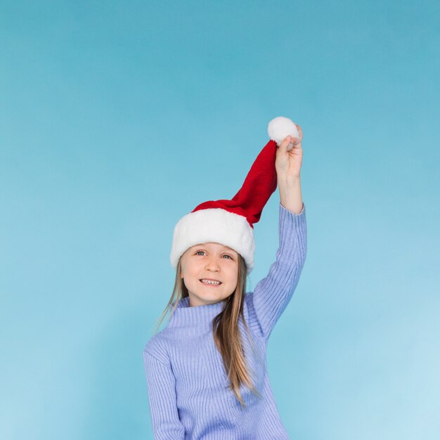 Cute little girl playing with a santa claus hat