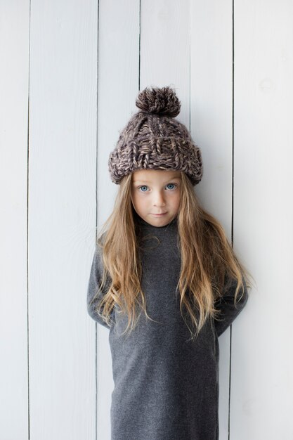 Cute little girl posing next to white wall