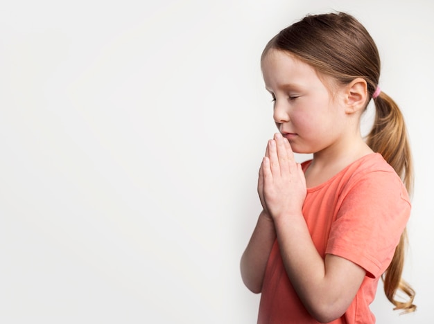 Милая маленькая девочка молится с копией пространства