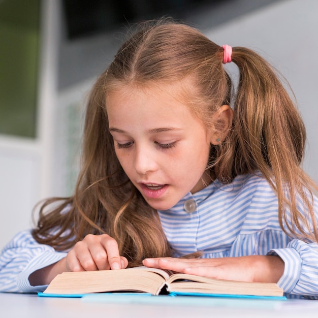 Free photo cute little girl reading in class