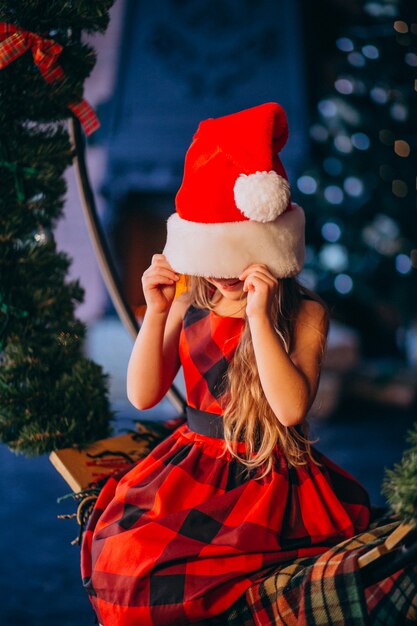 Милая маленькая девочка в новогодней шапке и красном платье