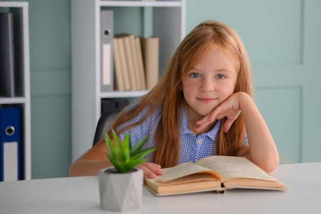 彼女の机で本と宿題をしているかわいい女の子の女子高生