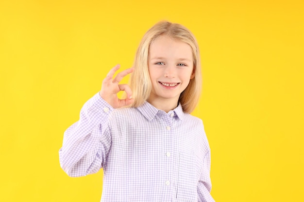 Cute little girl in shirt on yellow background