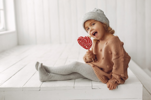 Милая маленькая девочка сидит и ест конфеты