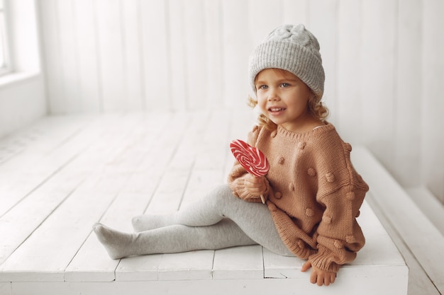 Free photo cute little girl sitting and eating candy