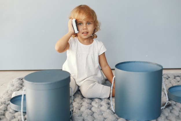 Bambina sveglia che si siede in uno studio con la scatola dei presente