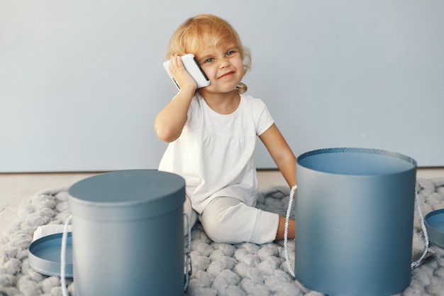 Free photo cute little girl sitting in a studio with presents box