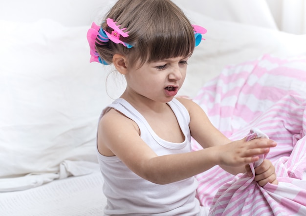 Cute little girl smiling while lying in a cozy white bed