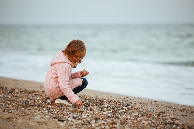 Милая маленькая девочка бросает камни