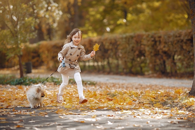 Cute little girl walks in a autumn park with a dog