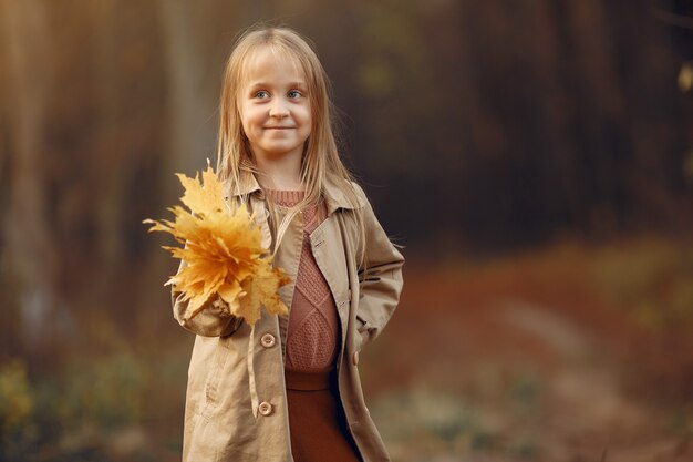 Милая маленькая девочка гуляет в осеннем парке