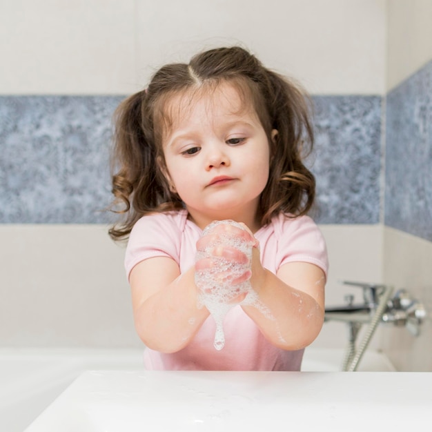Милая маленькая девочка моет руки