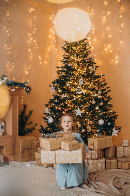 Cute little girl with christmas presents by the christmas tree