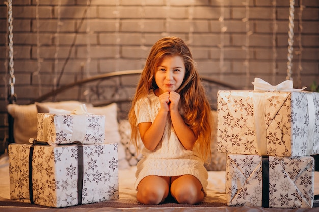 無料写真 クリスマスのかわいい女の子がベッドの中でプレゼントします。