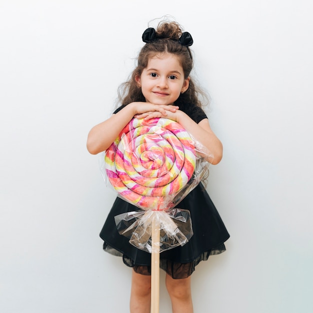 Бесплатное фото Милая маленькая девочка с гигантским леденцом на палочке