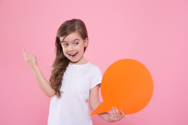 Cute little girl with an icon of a speech on a pink wall