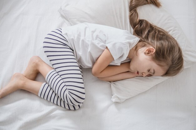 Cute little girl with long hair sleeping in bed.