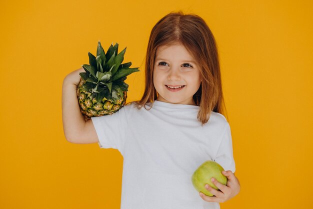 Cute little girl with pineapple and apple